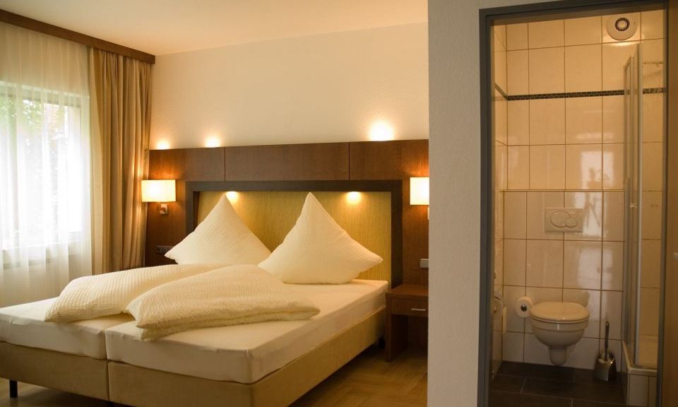 Doppelzimmer im Gaestehaus Birkenhof was die  Dependance des Weinhotel Kaisergarten darstellt hier Blick auf das Doppelbett und in das Badezimmer