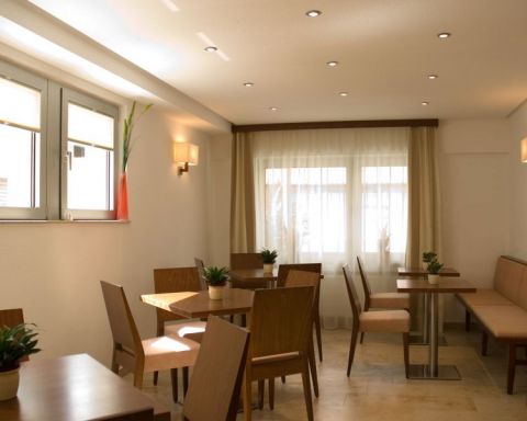 Aufenthalts und Fruehstuecksraum im Gaestehaus Birkenhof Steinboden grosse Fenster mehrere Tische und Stuehle 